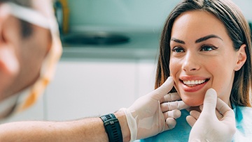 A dentist examines a female patient’s smile to determine which cosmetic dentistry solution is right for her