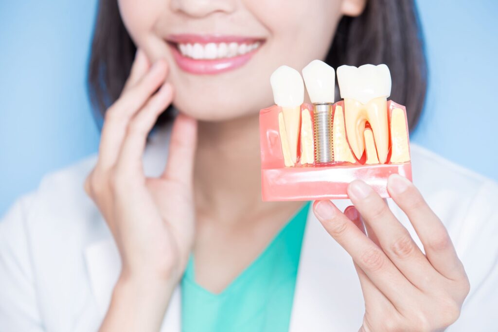 Nose-to-chest view of dentist holding sample implant and touching her own jaw